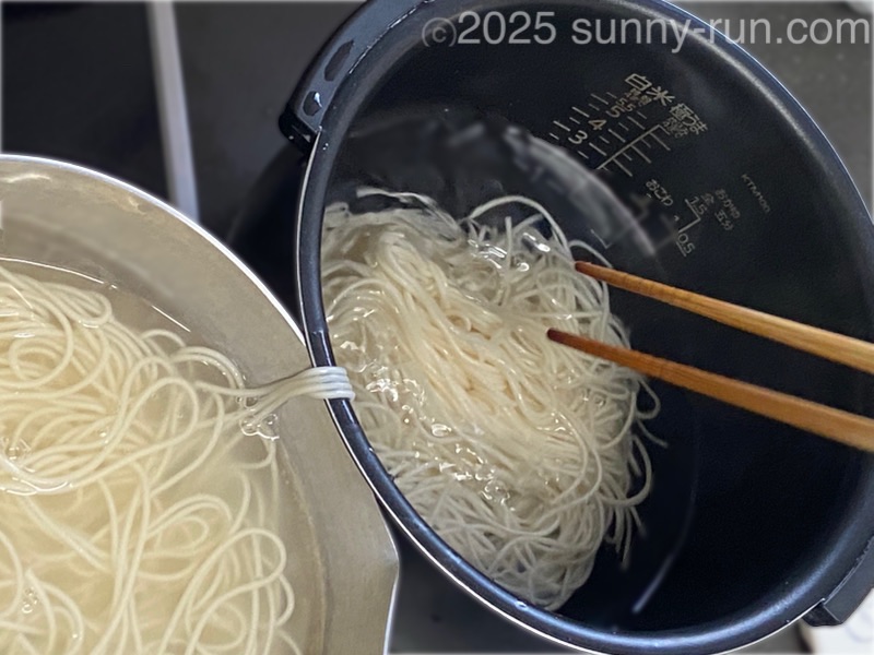 水を入れた炊飯釜に、茹でたそうめんを箸で移して“湯切り”する。炊飯釜にそうめんを入れた様子。