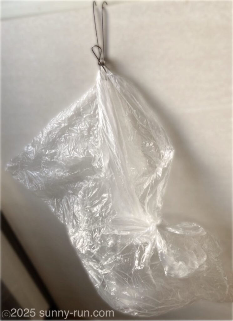 生協の袋を再利用したプラゴミ入れを、ステンレスピンチフックで挟んで吊り下げている