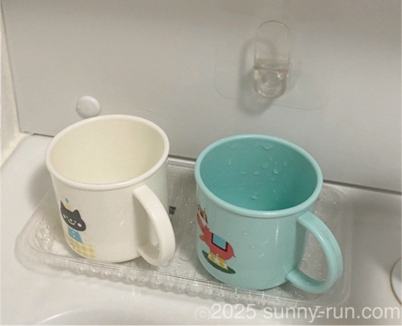 洗面台の「コップ置き」として使っている透明な食品トレーと、その上に並んだ２つのコップ