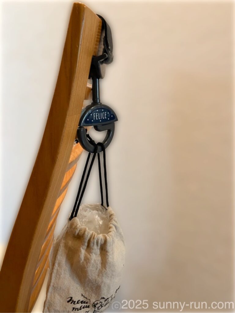 ダイニングの椅子の背もたれにベビーカーフックを付けて巾着袋を掛け、ポリ袋のストックを入れている。