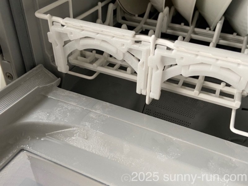 食洗機の庫内に下洗いした皿を入れている様子。開いた扉などが濡れている。
