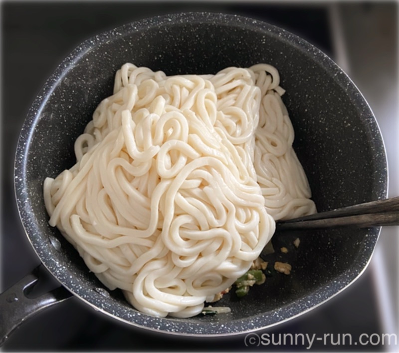 残りおかずが入ったフライパンに、市販のゆでうどん4玉を投入した様子
